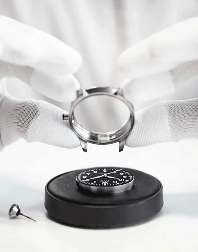 A white-gloved watchmaker servicing a watch case in our workshop.