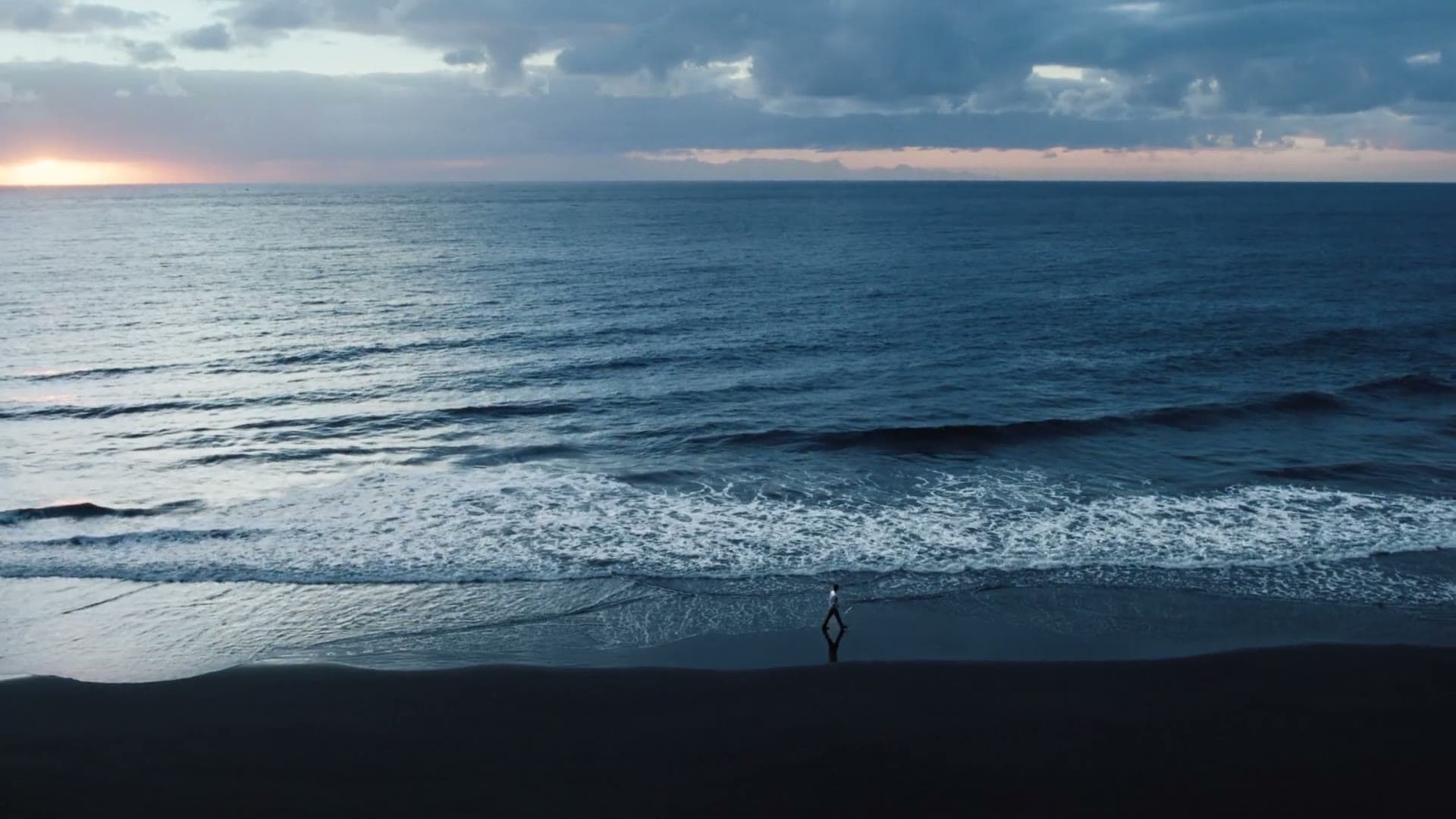 Longines film still, a lone figure on a beach at dusk